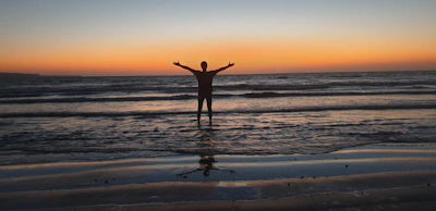 a person standing on a beach at sunset