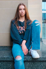 a woman sitting on a ledge with her legs crossed