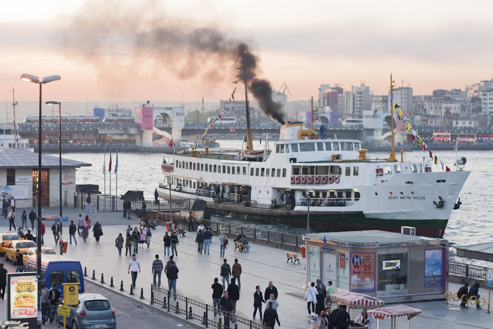 a group of people walking along a pier next to a boat