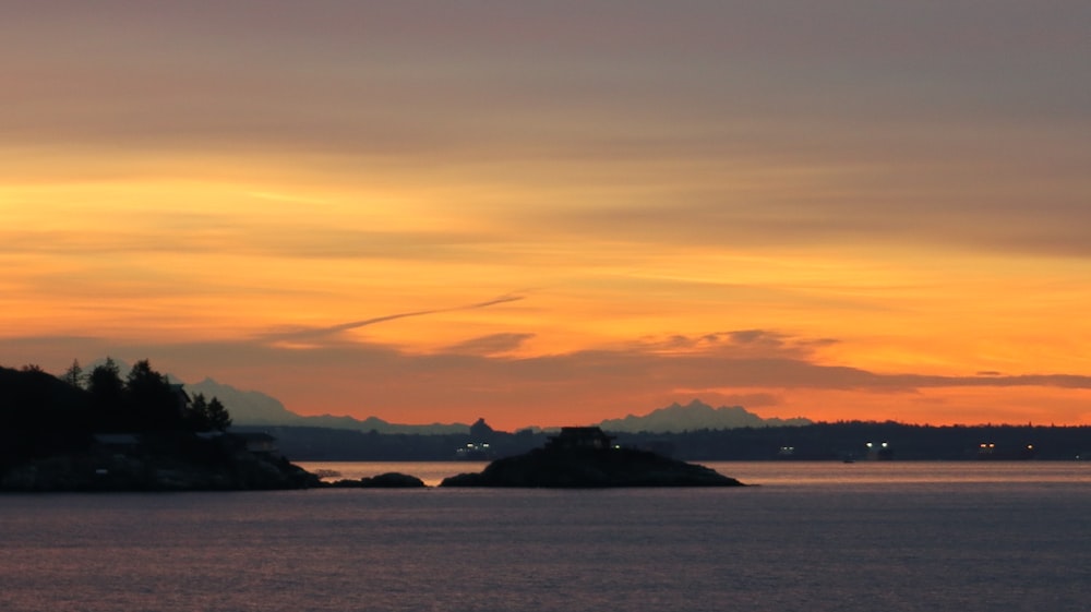 山を背景にした水域に沈む夕日