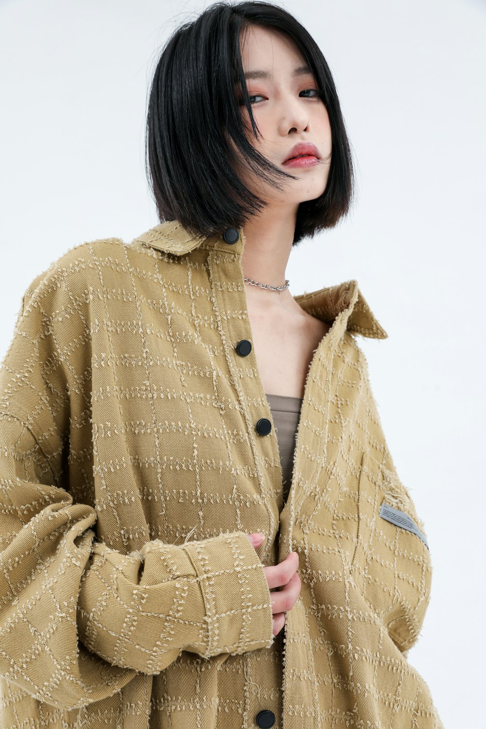 a woman with black hair wearing a brown jacket