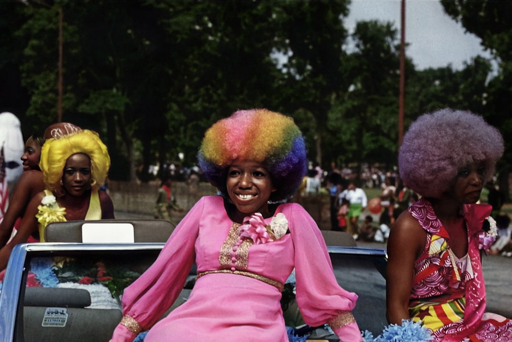 a woman in a pink dress sitting on the back of a car