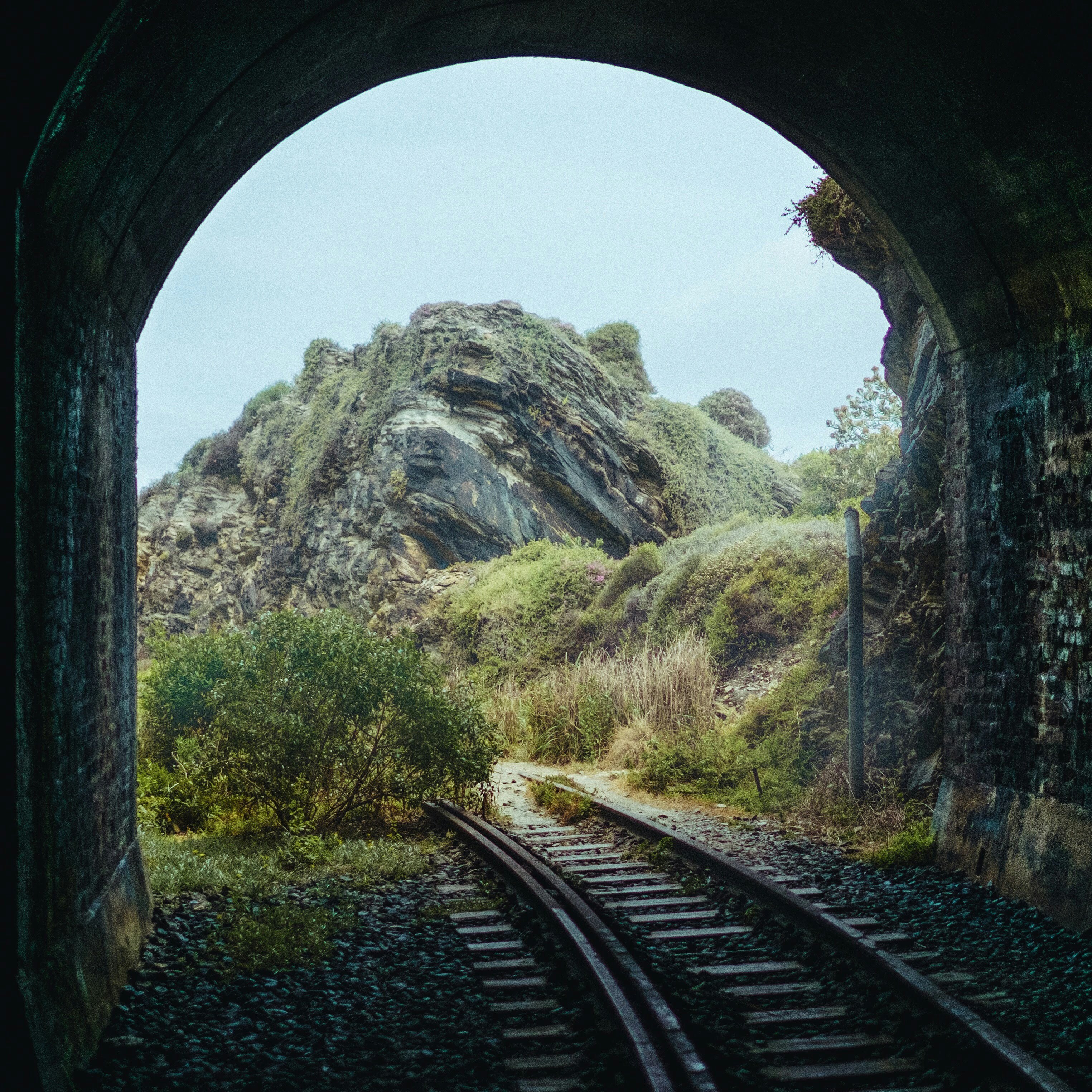 a train track going through a tunnel with a mountain in the background