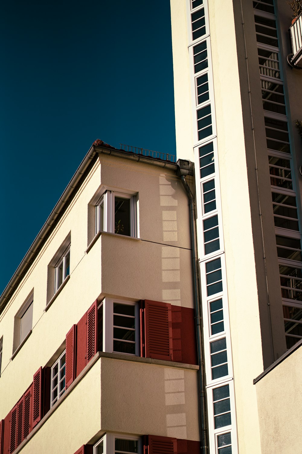 a tall building with red shutters next to a tall building