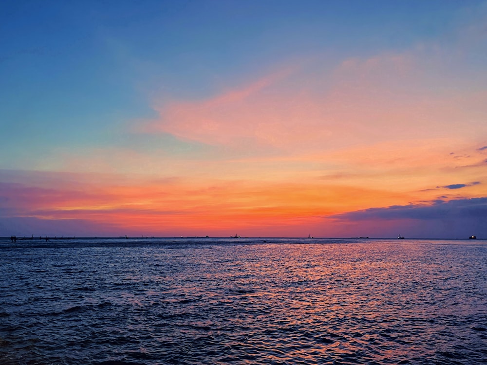 a sunset over a body of water with boats in the distance