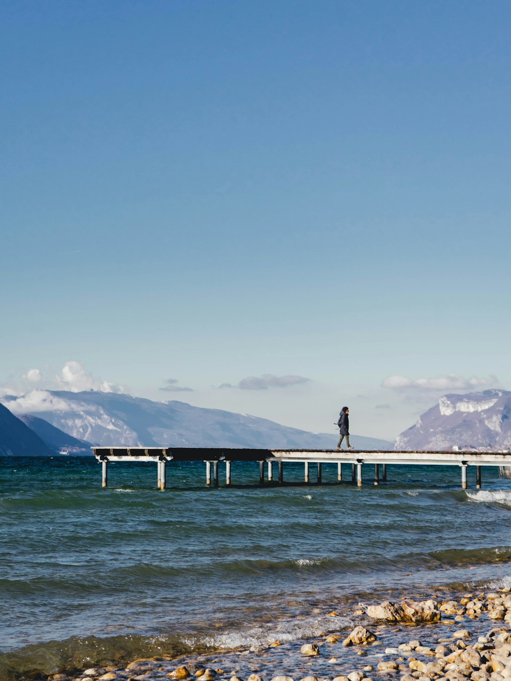 a man walking across a bridge over a body of water