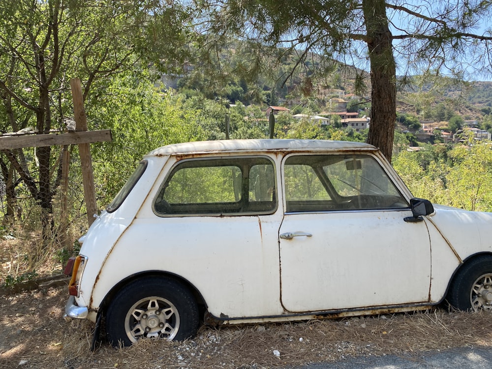 an old white car is parked in the woods