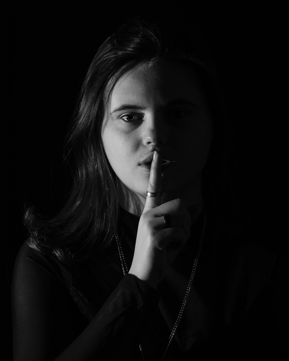 a woman is holding her finger to her lips