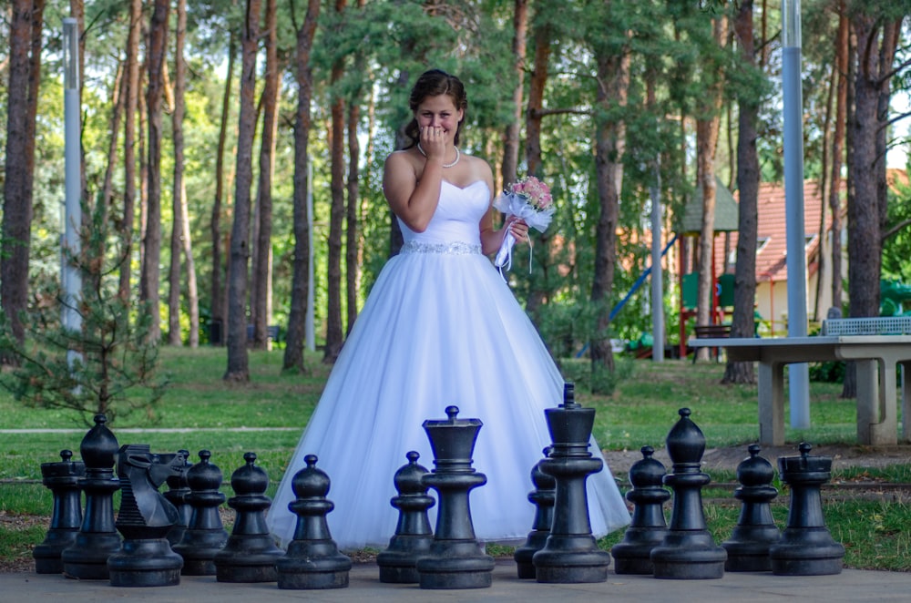 a woman in a wedding dress standing next to a giant chess set