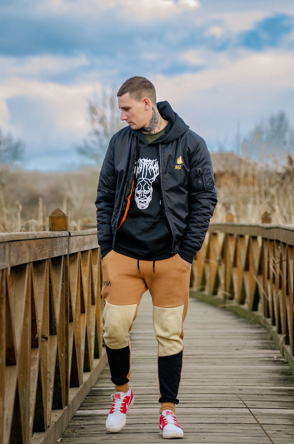 a man standing on a wooden bridge with his hands in his pockets