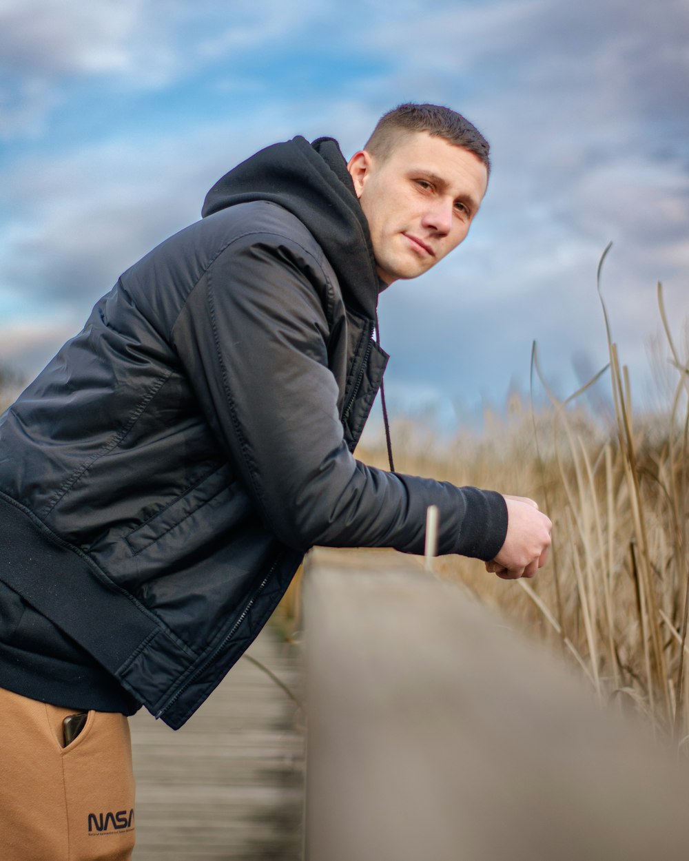 a man leaning on a fence in a field