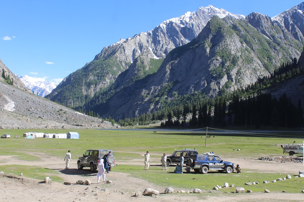 a group of people standing in a field next to a mountain