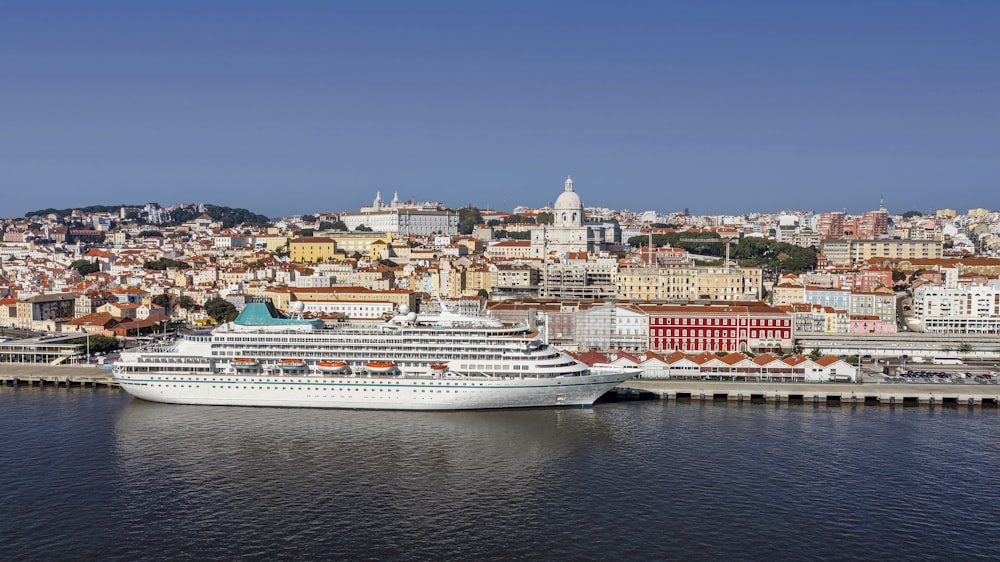 a cruise ship docked in a harbor with a city in the background