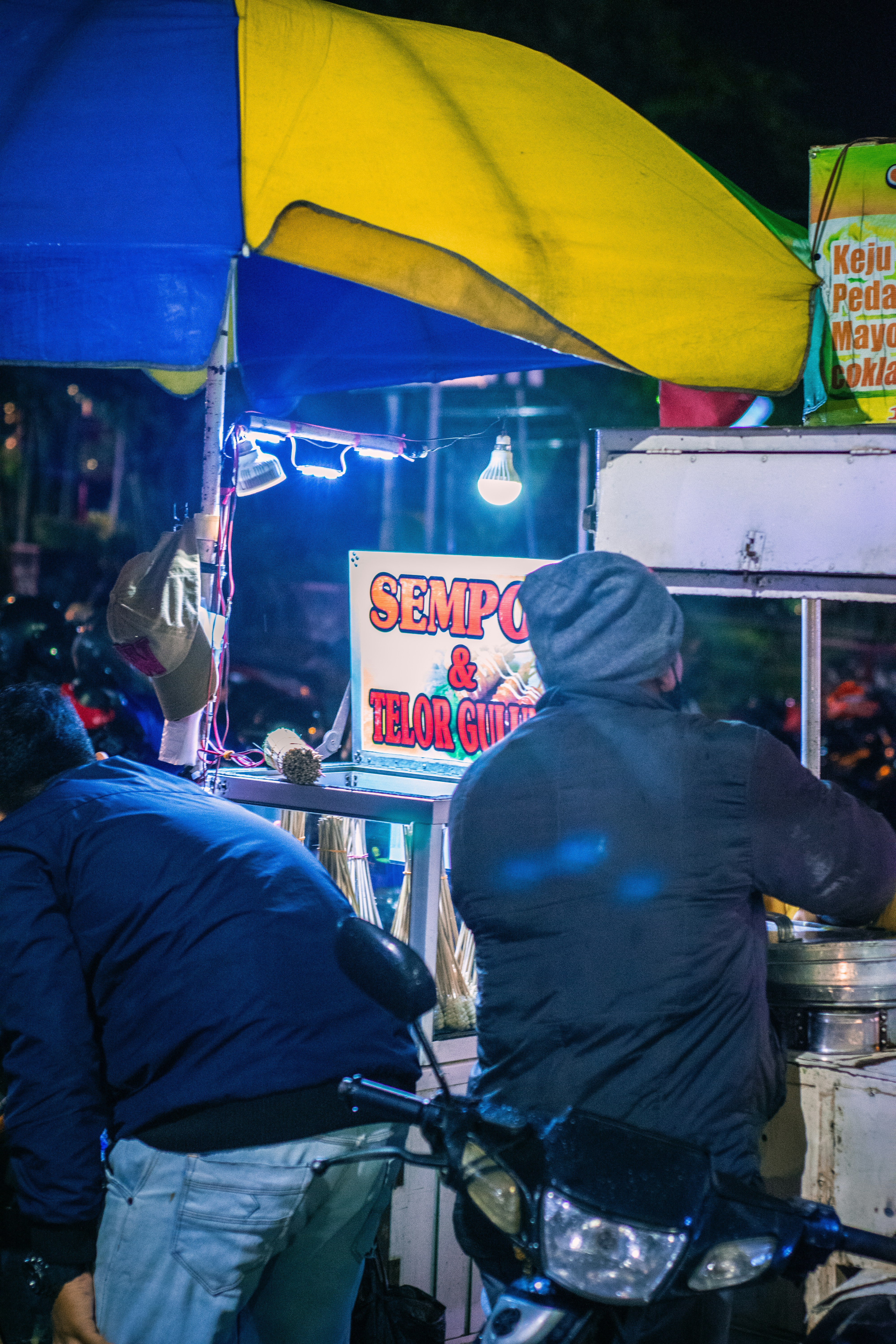 sekelompok orang berdiri di sekitar gerobak makanan