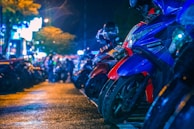 A row of custom motorcycles gleaming under the neon lights of a nighttime biker meet.