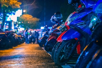 A row of custom motorcycles gleaming under the neon lights of a nighttime biker meet.