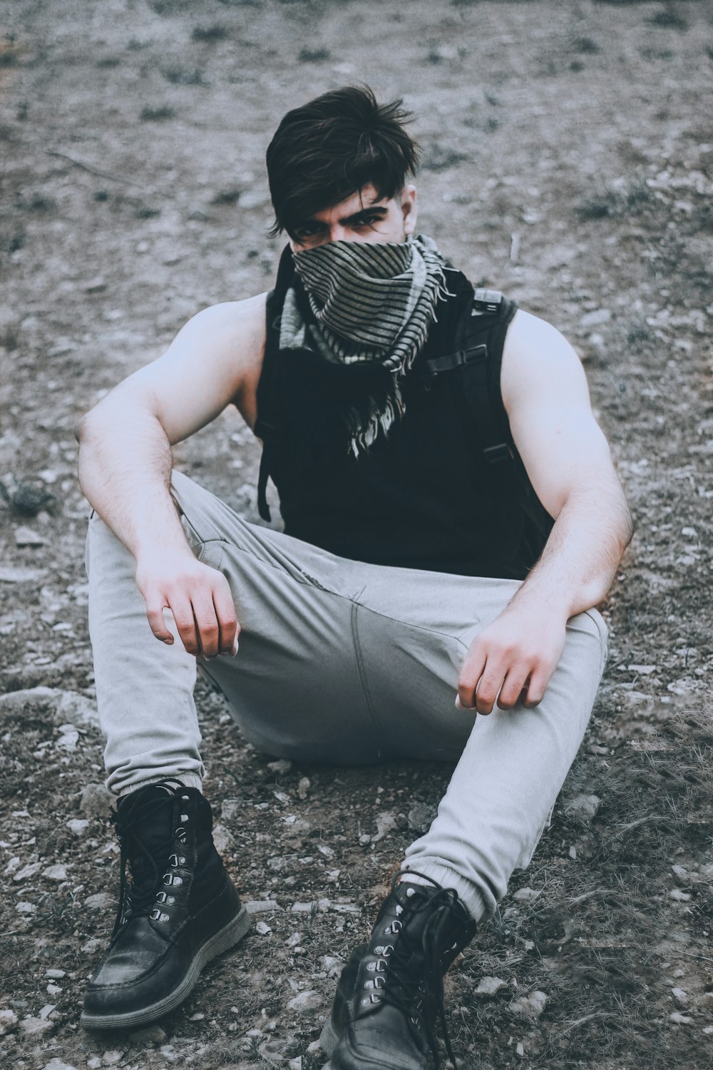 a man sitting on the ground wearing a mask