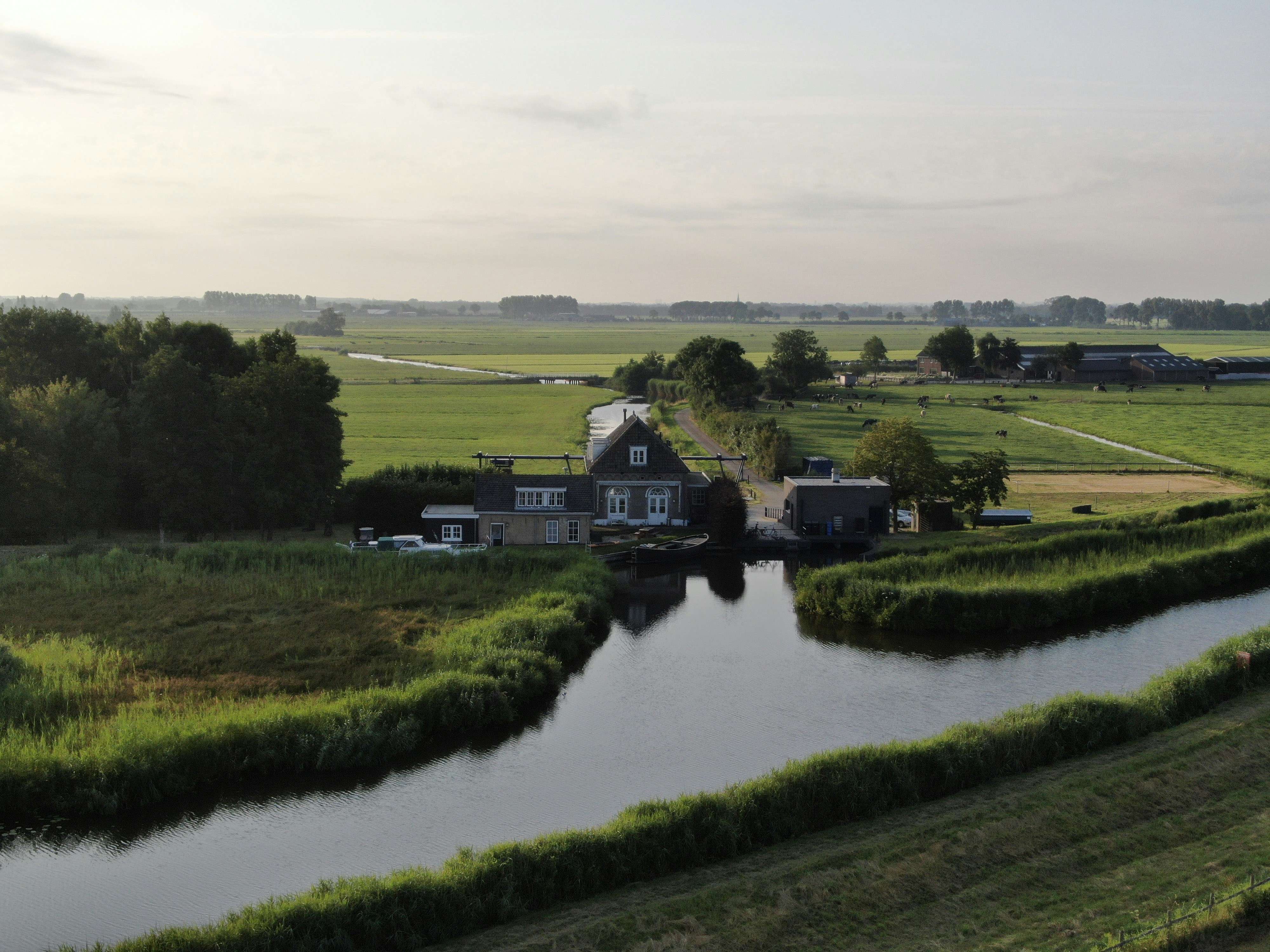 Aerial view of Netherlands countryside with waterways and flat green fields, overcast sky, muted colors, dark atmospheric
