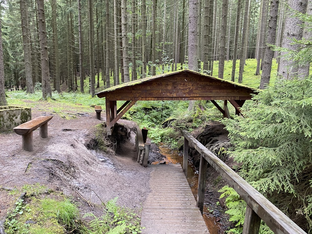 a wooden gazebo in the middle of a forest