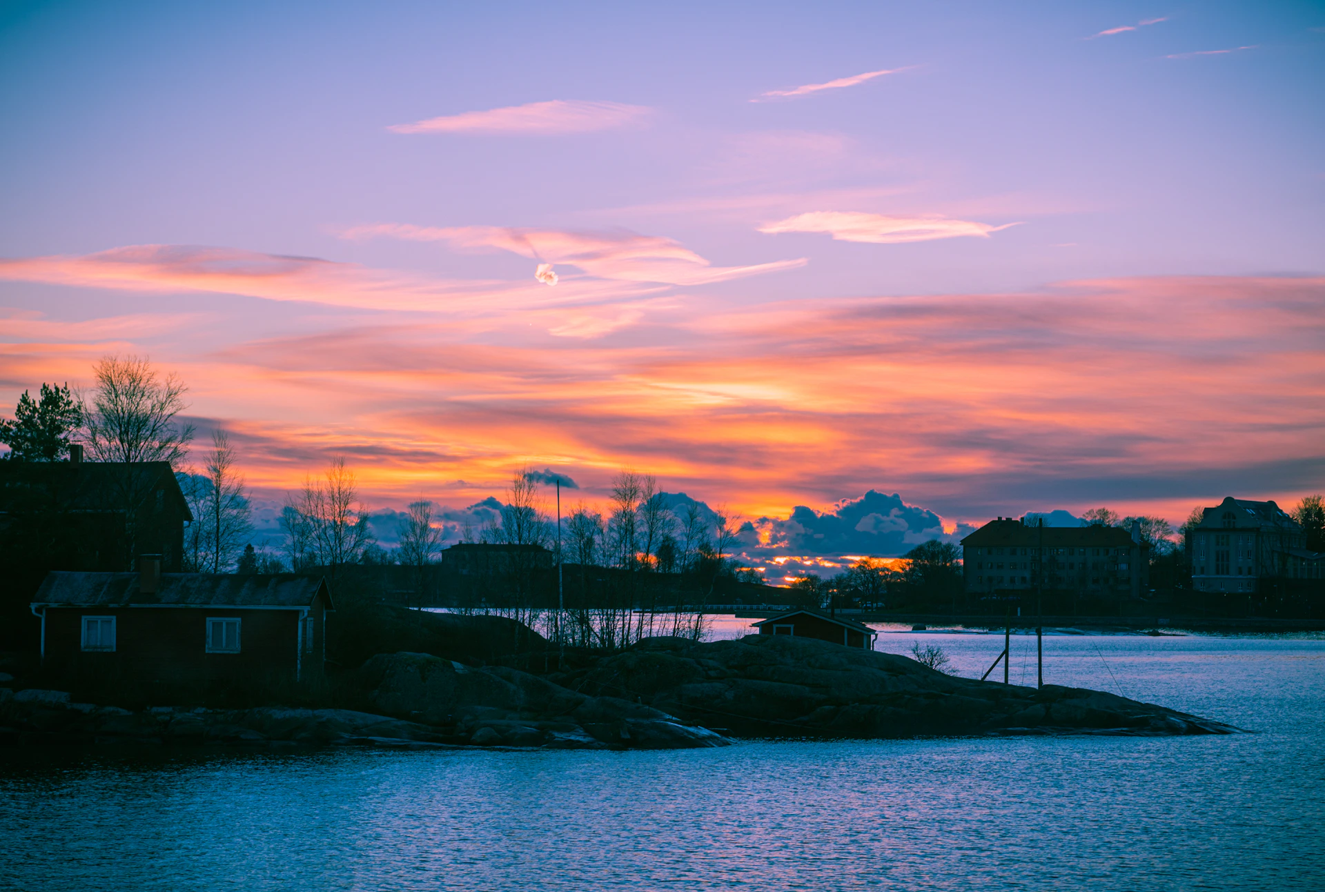 a sunset over a body of water with houses in the background