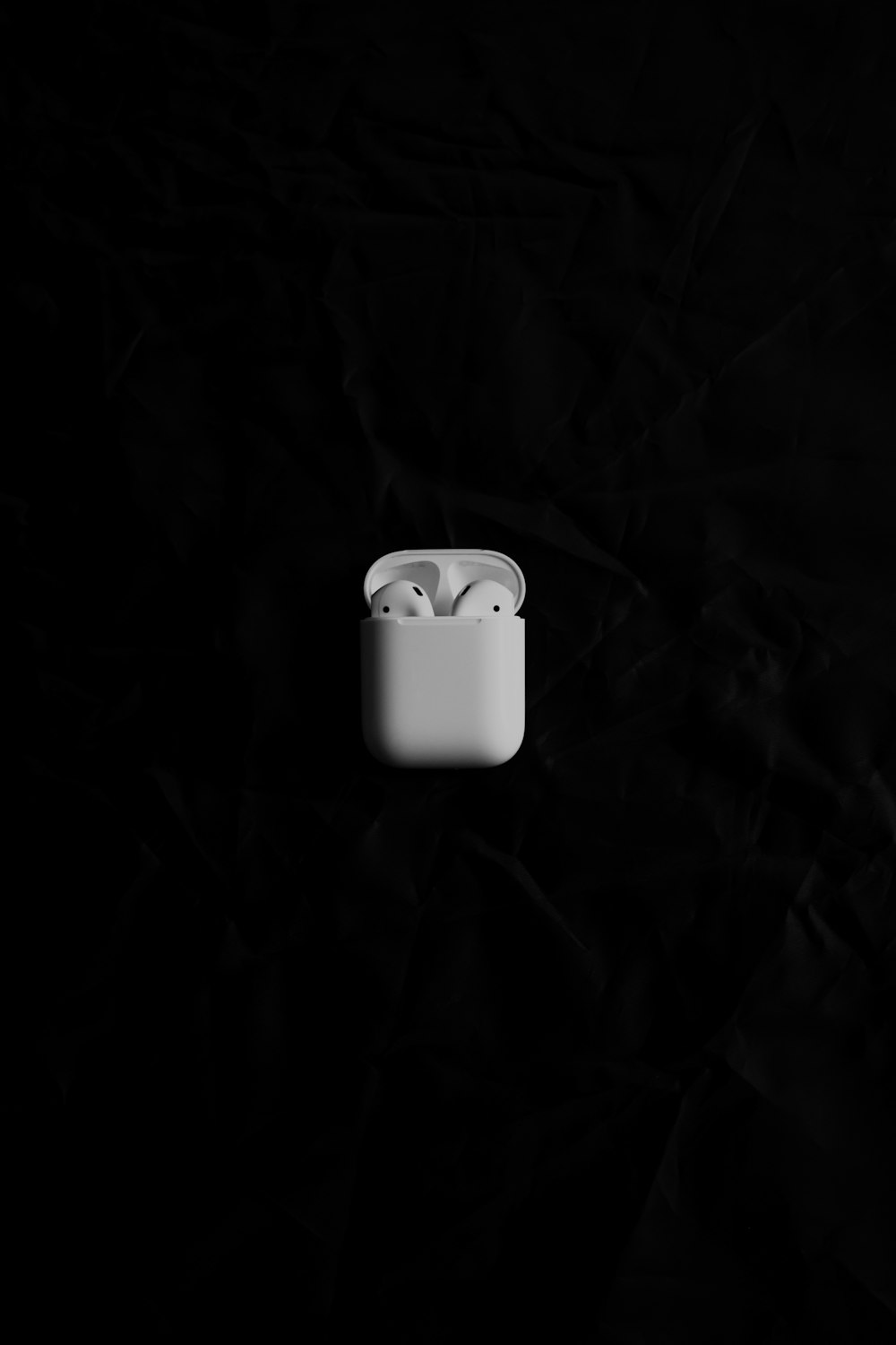 黒い表面の上に座っている白いリンゴのAirPods