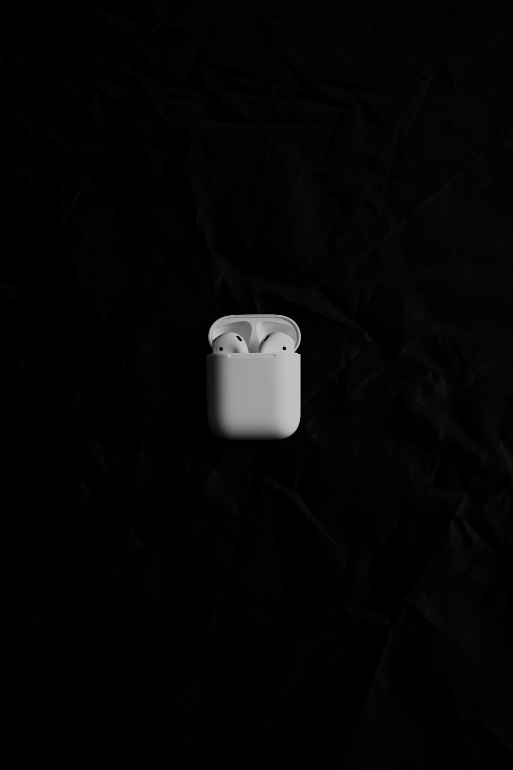 Un AirPods Apple bianco seduto sopra una superficie nera