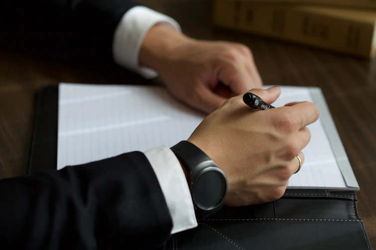 A person in a suit writing on a document.