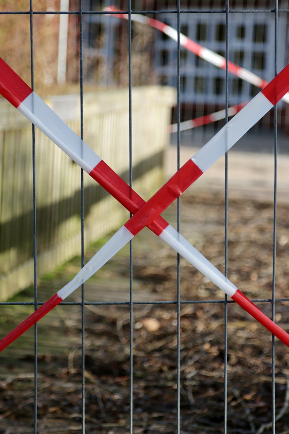 ein Zaun mit zwei rot-weißen Klebebändern, die um ihn gewickelt sind