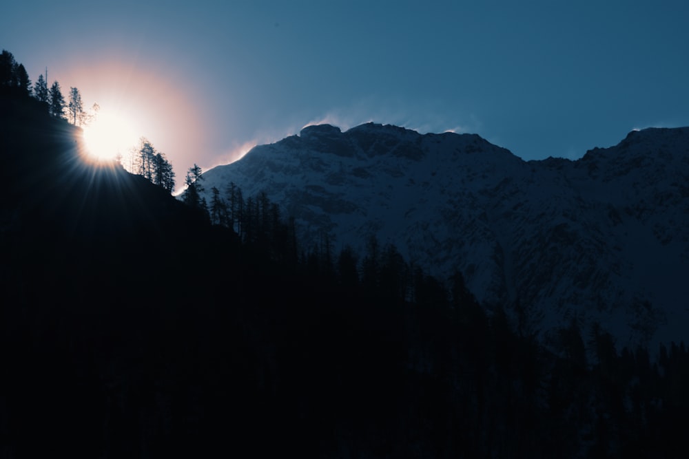 the sun is shining through the clouds over the mountains