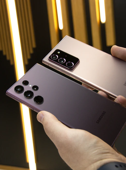 A close-up of hands comparing two smartphones under natural light