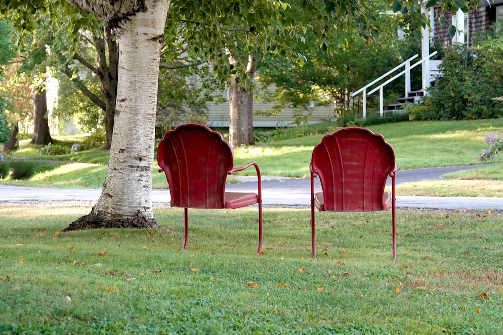 a couple of red chairs sitting on top of a lush green field