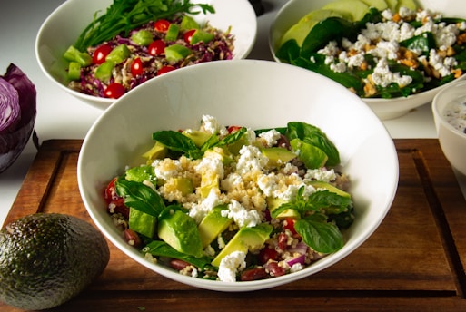 three bowls of salad on a cutting board