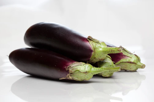 Deep purple eggplants with glossy skins arranged artfully on rustic wood.