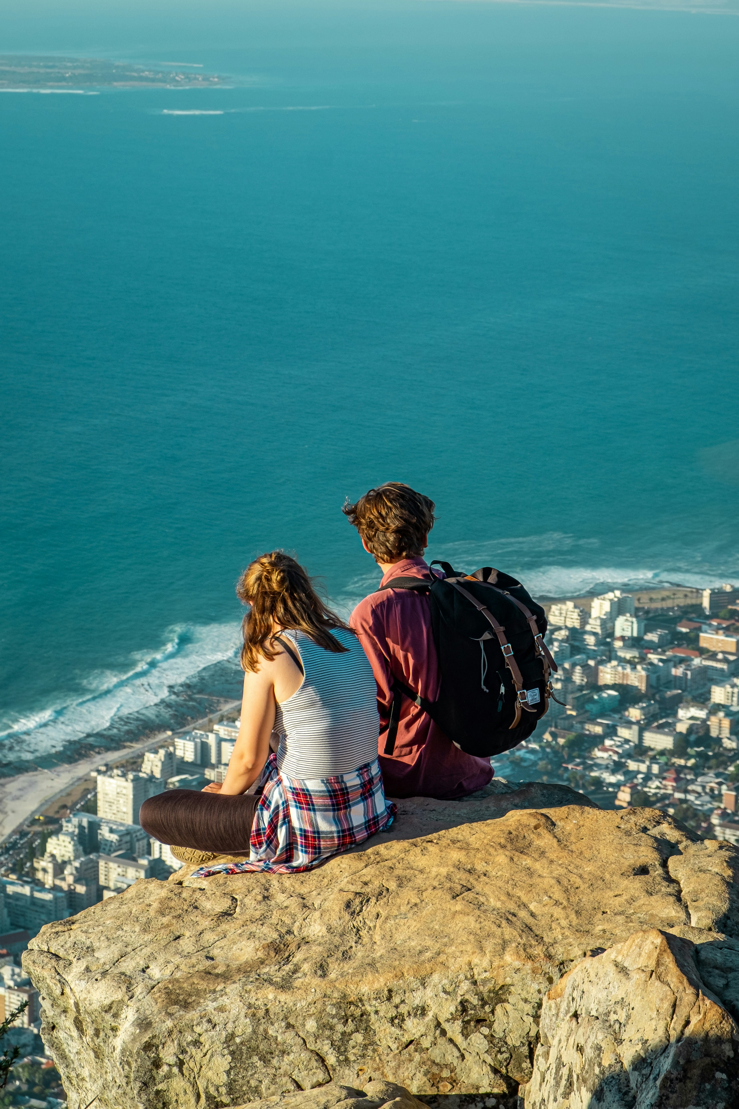 a couple of people sitting on top of a cliff