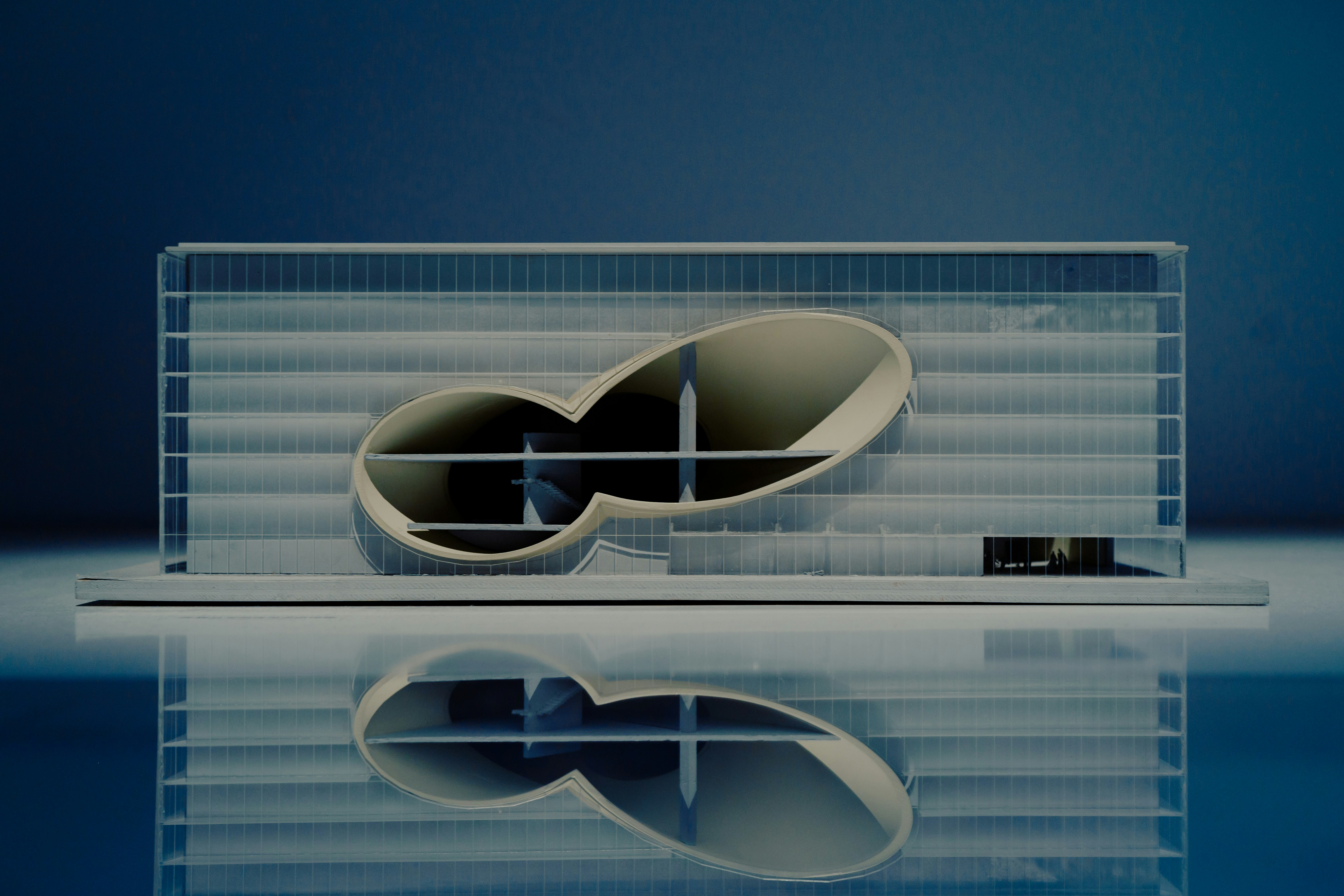 Modern building architectural model with gridded facade on reflective surface.