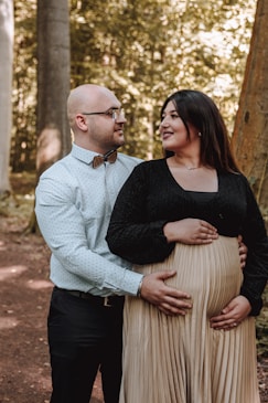 a pregnant woman and a man standing in the woods