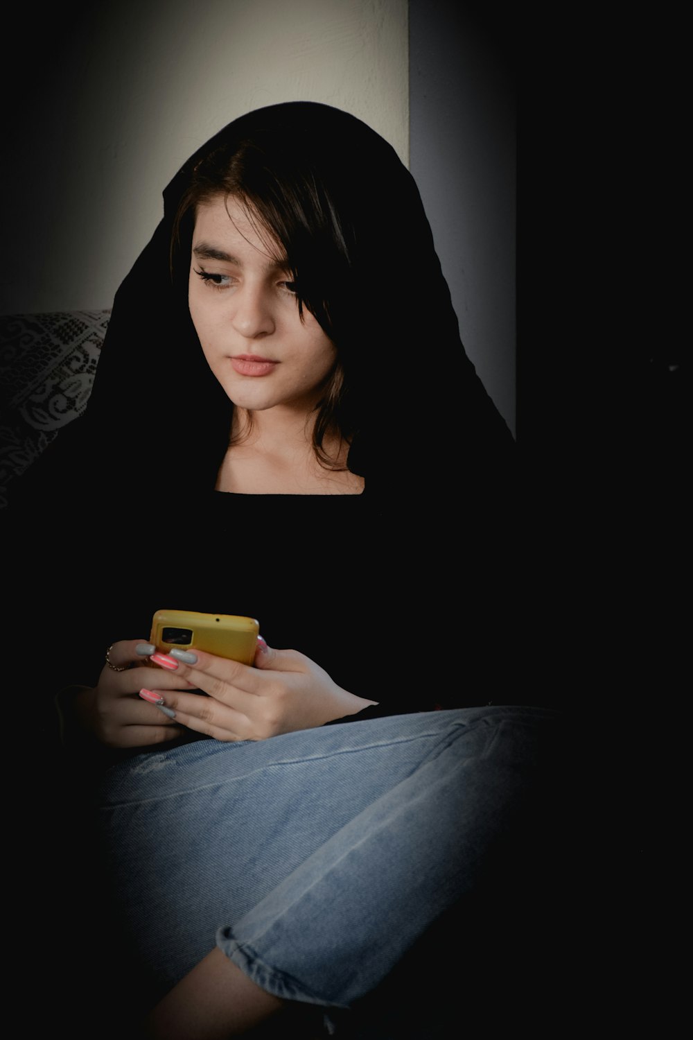 a woman sitting on a couch looking at her cell phone