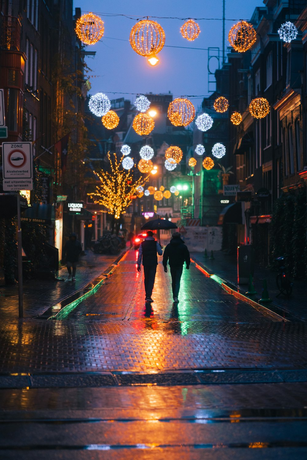 a couple of people walking down a street at night