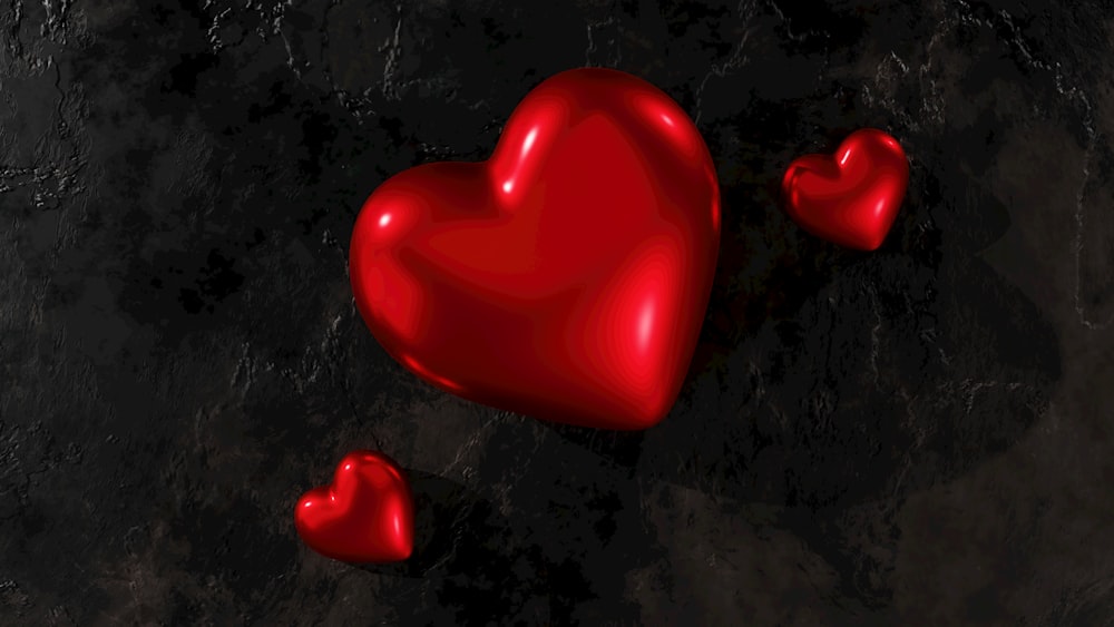Eine Gruppe roter Herzen, die auf einer schwarzen Oberfläche sitzen