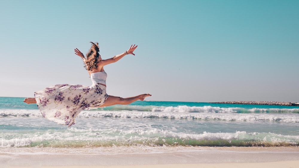 a woman jumping into the air at the beach