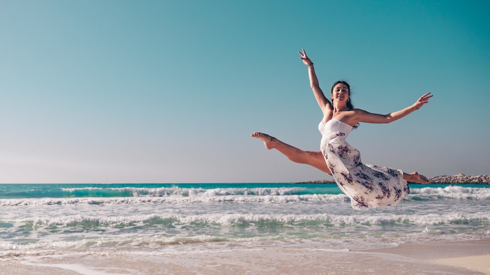 a woman jumping in the air on the beach