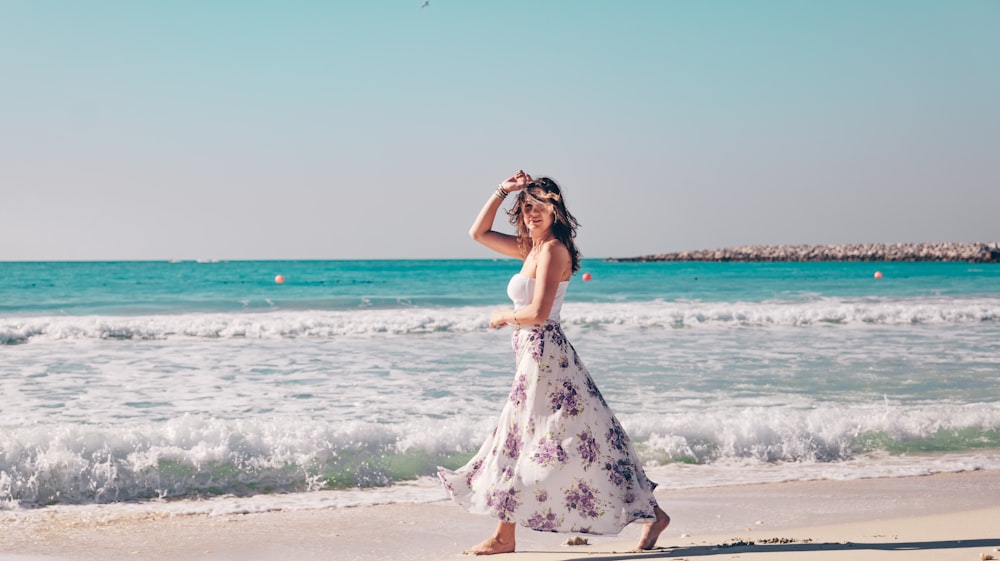 a woman in a long dress walking on the beach