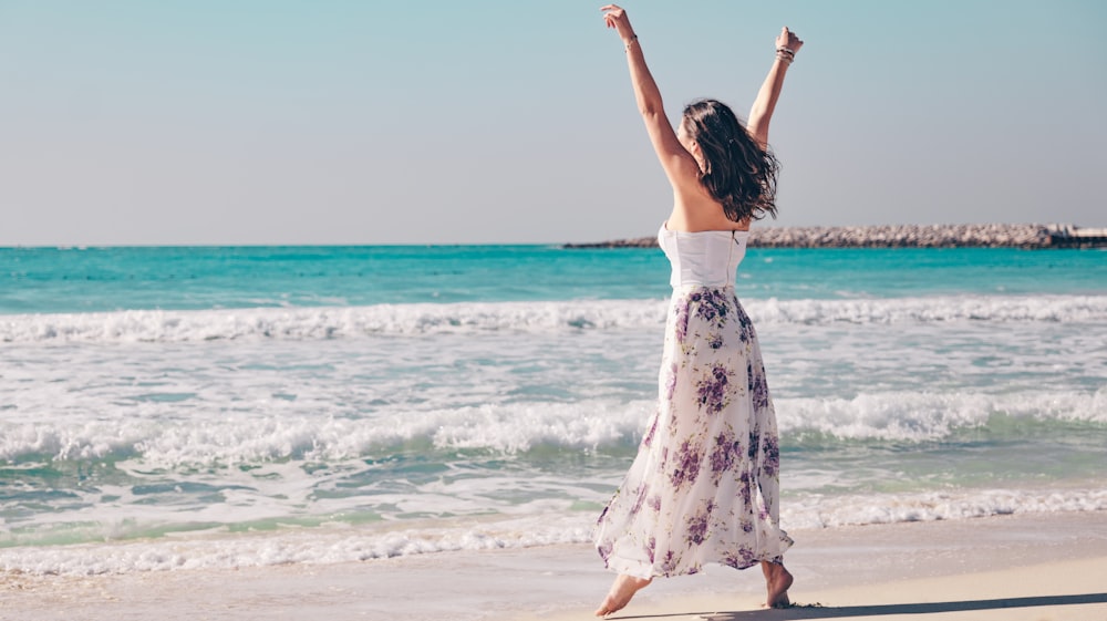 a woman standing on a beach with her arms in the air