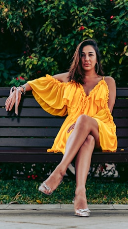 A stylish woman wearing a vibrant summer dress in a sunny park.