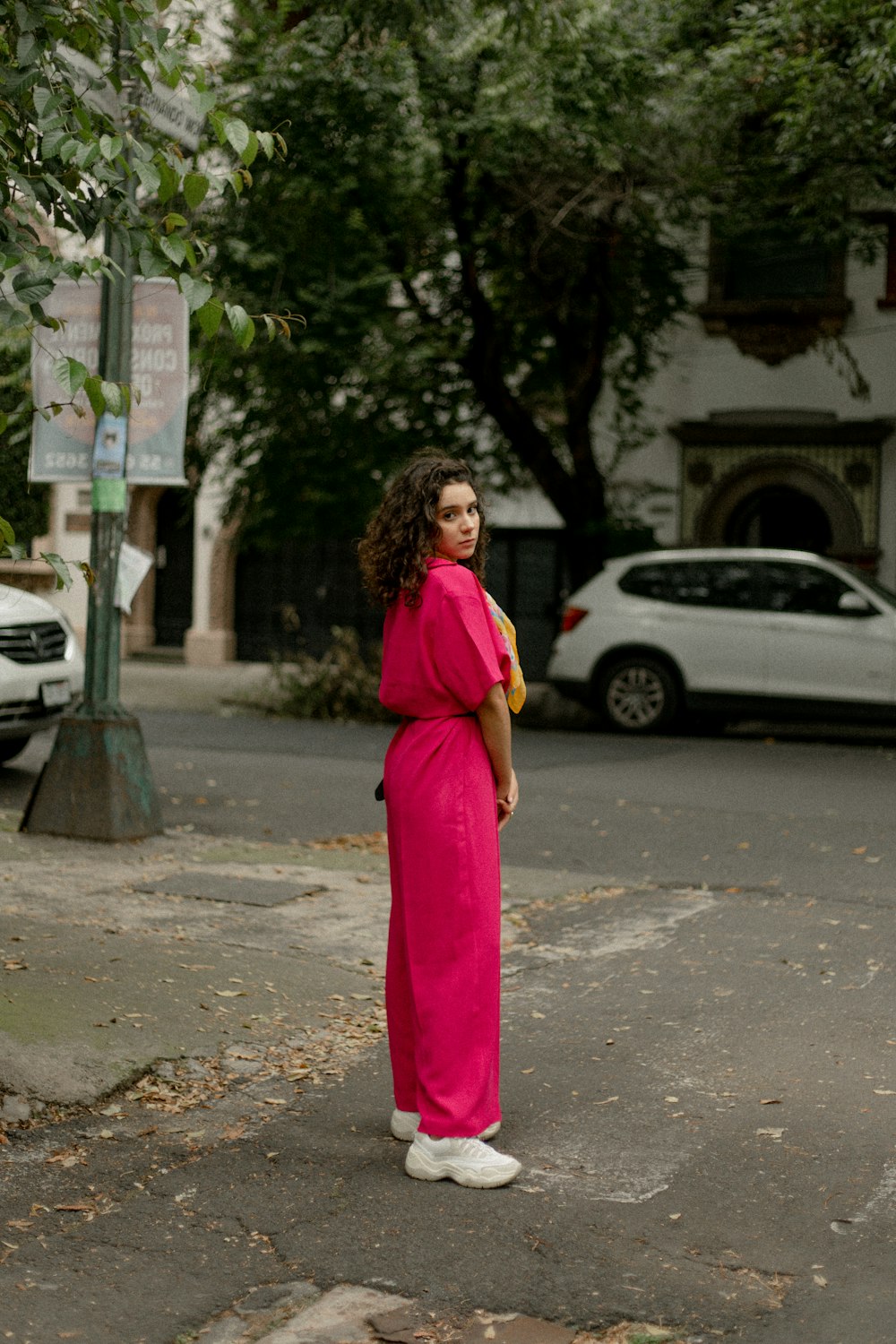 Une femme en robe rose debout au coin d’une rue
