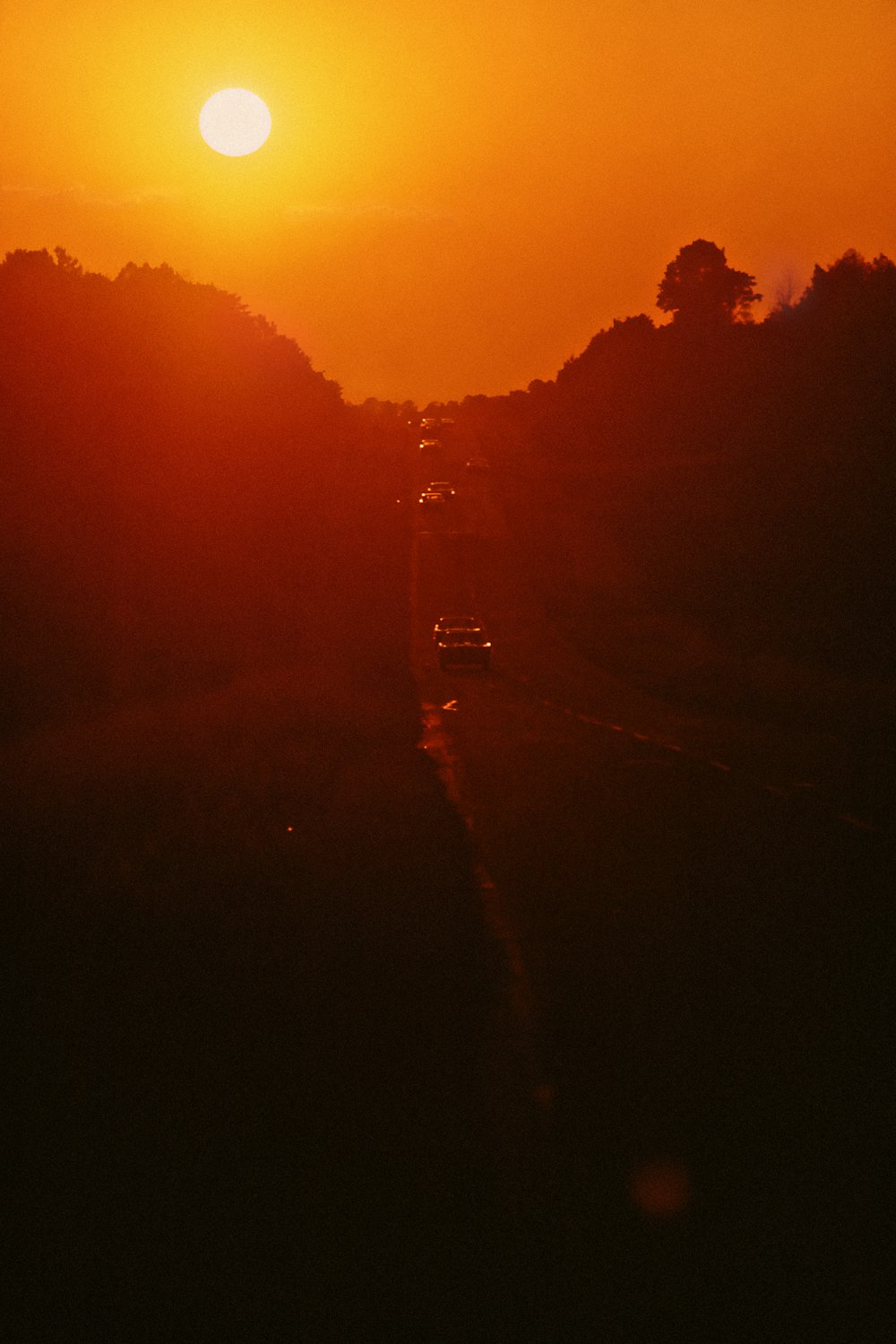 the sun is setting over a road with cars on it