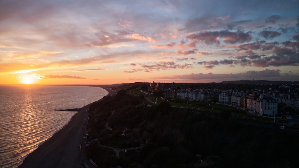 the sun is setting over the ocean and a beach