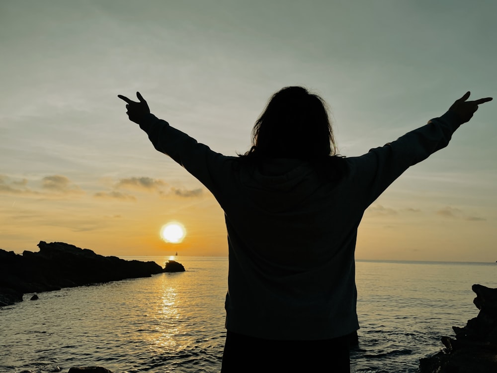 a person standing on a beach with their arms outstretched