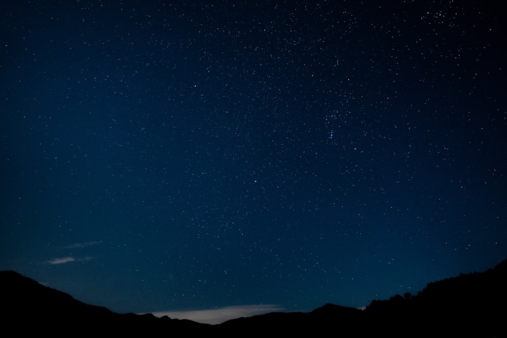 the night sky with stars above a mountain range