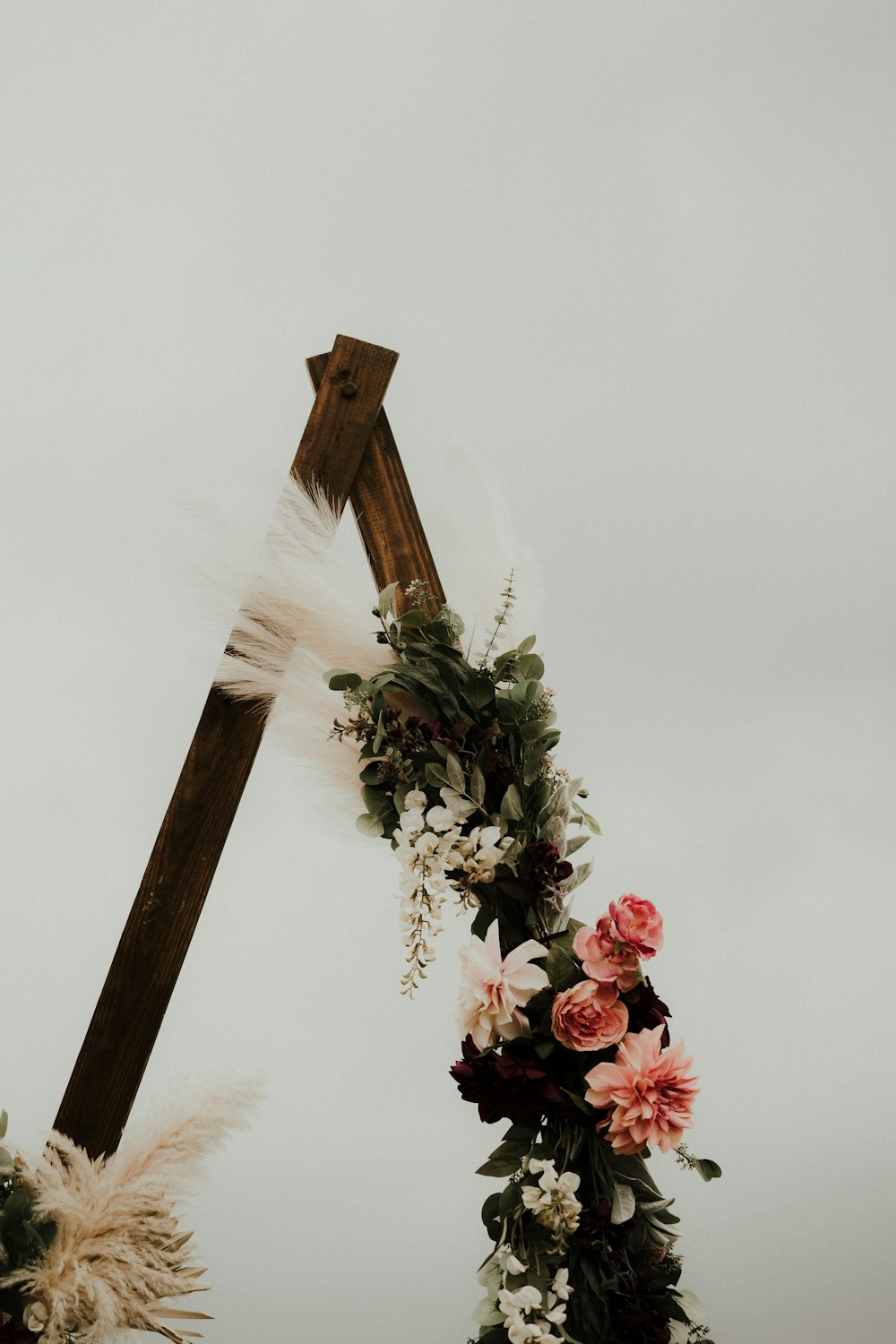 una cruz de madera decorada con flores y plumas